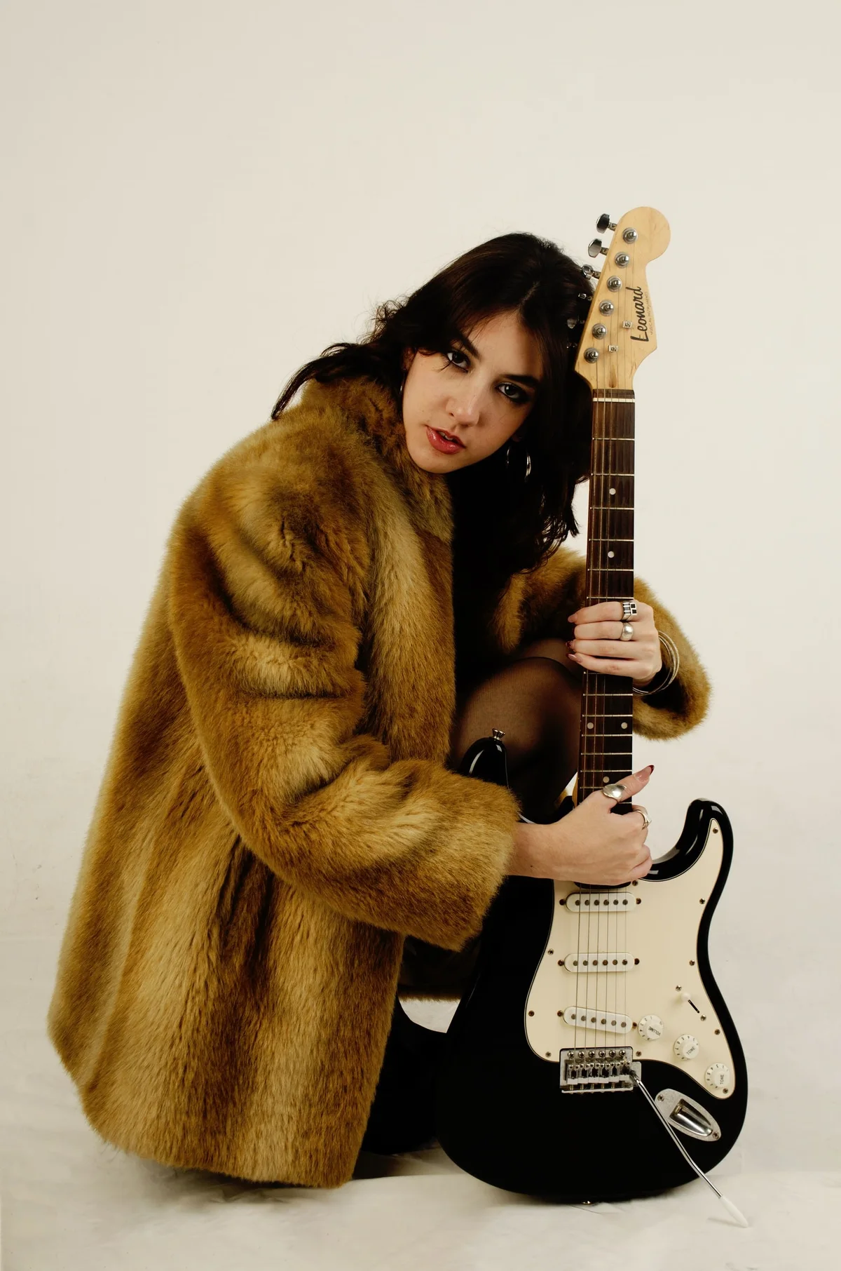 Modelo arrodillada con tapado de piel y guitarra eléctrica