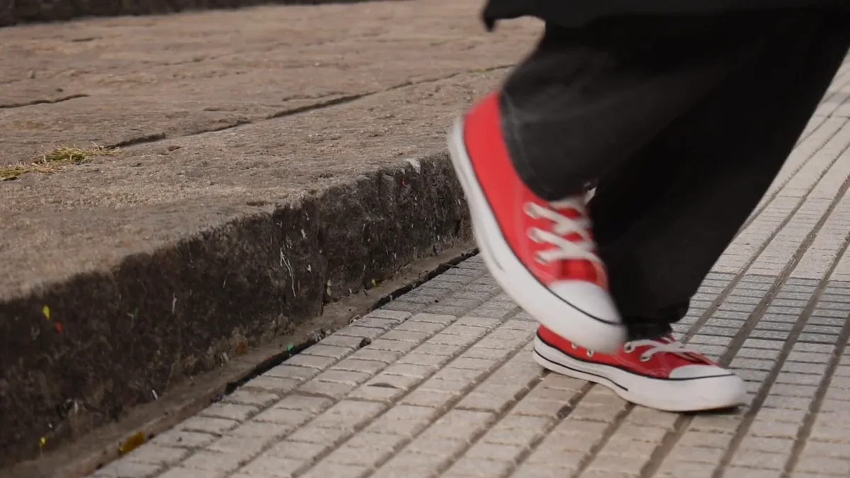 Fotograma del fashion film: zapatillas rojas caminando sobre la vereda